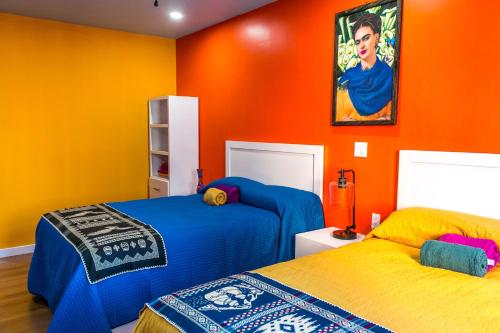 ein Schlafzimmer mit 2 Betten und einer orangefarbenen Wand in der Unterkunft Hotel Cantaritos in Rosarito