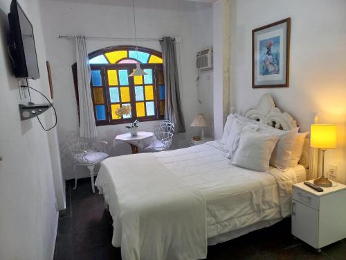 a bedroom with a white bed and a stained glass window at Pousada do Sossego Conceição de Jacareí in Mangaratiba