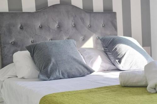 1 cama con almohadas blancas y cabecero gris en Villa Lux Finestrat, en Finestrat