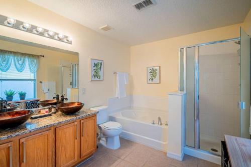a bathroom with a tub and a sink and a toilet at 5 Bedroom Villa l 12 min to Disney l Themed Rooms l Orlando Area in Davenport
