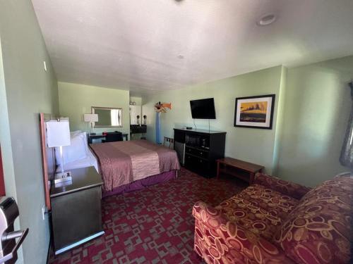 Rancho California Inn Temecula في تيميكولا: غرفه فندقيه بسرير واريكه
