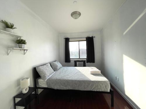 a small bedroom with a bed and a window at 2BR elevator APT 10min to LGA airport 1min to train! in Queens