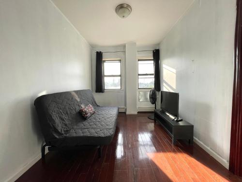 a living room with a couch and a television at 2BR elevator APT 10min to LGA airport 1min to train! in Queens