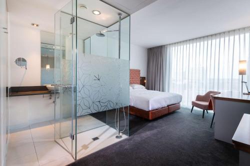 um quarto com uma cabina de duche em vidro e uma cama em DoubleTree by Hilton Frankfurt Niederrad em Frankfurt