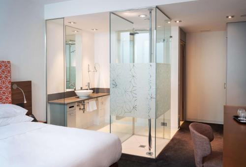 a bedroom with a glass shower and a bed at DoubleTree by Hilton Frankfurt Niederrad in Frankfurt/Main