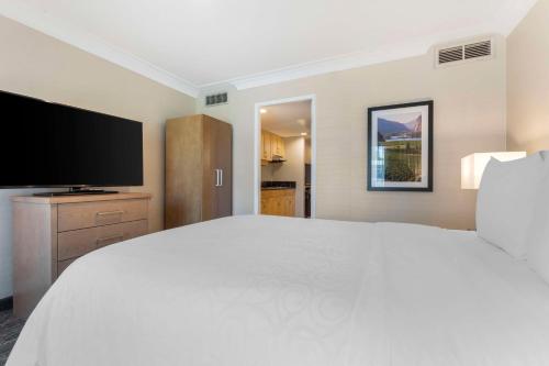 a bedroom with a large white bed and a flat screen tv at Best Western Plus Kelowna Hotel & Suites in Kelowna