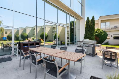 a patio with a table and chairs and a grill at Best Western Plus Kelowna Hotel & Suites in Kelowna