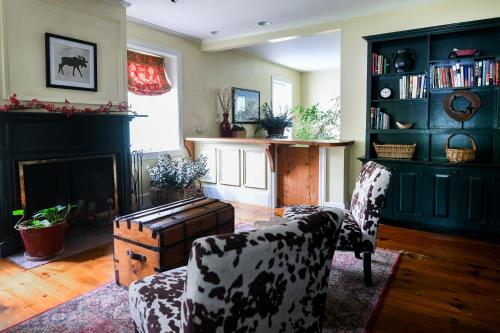 a living room with two chairs and a fireplace at 1820 House - VT Charm + Modern Comforts + Hot Tub in Stowe
