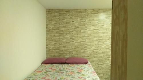 a bed in a room with a brick wall at Winterville Flat 905 in Gravatá