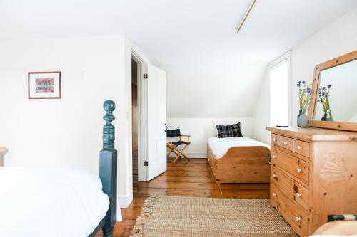 a bedroom with a bed and a dresser and a mirror at 1820 House - VT Charm + Modern Comforts + Hot Tub in Stowe