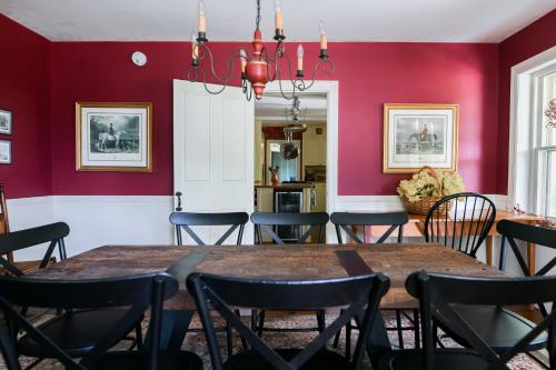 a dining room with red walls and a table and chairs at 1820 House - VT Charm + Modern Comforts + Hot Tub in Stowe