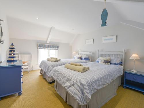 two beds in a bedroom with blue and white sheets at Prydes Cottage in Saint Mawes