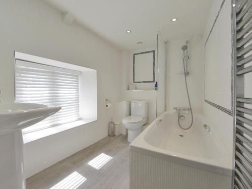 a white bathroom with a tub and a toilet at Prydes Cottage in Saint Mawes