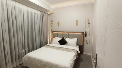 a bedroom with a bed with white sheets and black pillows at Alzahaby Apartmen Sakarya CADDE54 in Serdivan