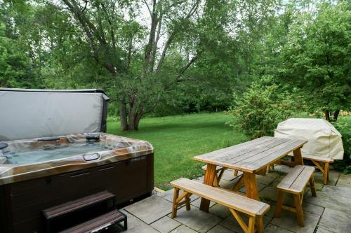 a hot tub and a picnic table on a patio at 1820 House - VT Charm + Modern Comforts + Hot Tub in Stowe
