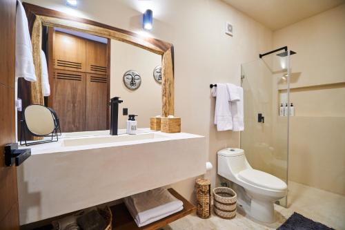 een badkamer met een wastafel, een toilet en een spiegel bij Spacious & Comfy Penthouse Oasis with Plunge Pool in Tulum