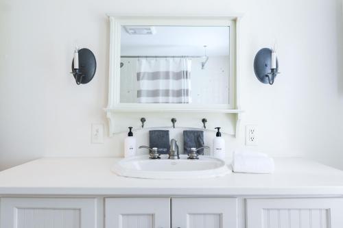 a white bathroom with a sink and a mirror at 1820 House - VT Charm + Modern Comforts + Hot Tub in Stowe