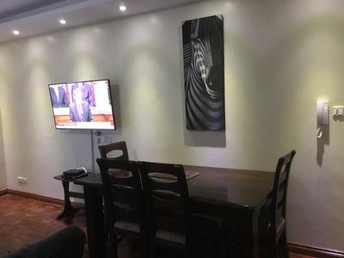 a dining room with a table and a flat screen tv at Jancy Properties in Nairobi