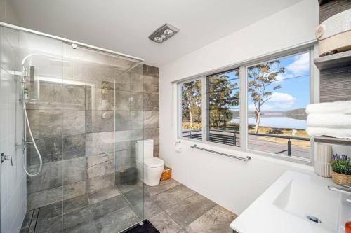 baño con ducha, lavabo y ventana en Lakefront dream stay w/Pool close to Blueys beach., en Smiths Lake