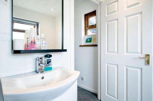Baño blanco con lavabo y espejo en Modern 3 Bedroom House Close to Ferry and City Centre, en Belfast