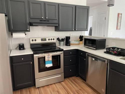 a kitchen with black cabinets and stainless steel appliances at Modern home steps to historic downtown Salisbury in Salisbury