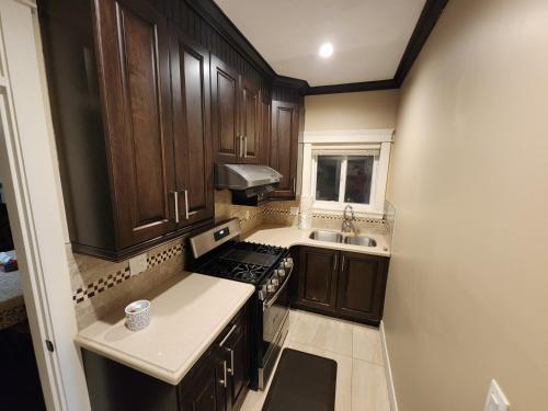 a small kitchen with wooden cabinets and a sink at Harmony Hospitality "Walking Distance to Surrey Central" in Surrey