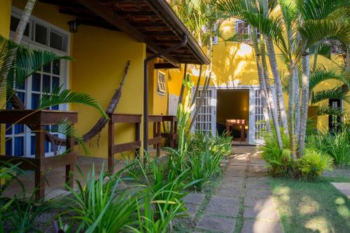 a yellow house with palm trees and a pathway at Villa Bella Ferradura in Búzios