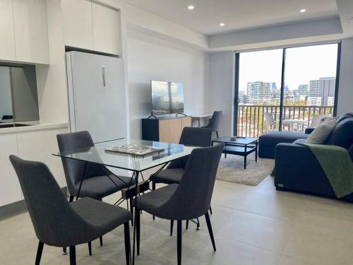 a living room with a glass table and chairs at Cosy Stays 1 Bedroom Apartment Rosebery Parking & Balcony Sydney Escape in Sydney
