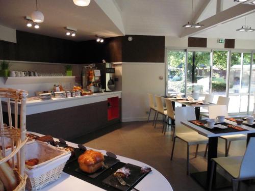 a restaurant with tables and chairs and a kitchen at Logis Hôtel Domaine du Moulin Cavier - Restaurants & Spa in Avrillé