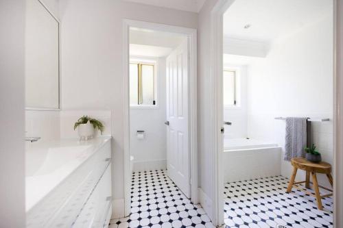 uma casa de banho com uma banheira branca e piso em azulejo preto e branco. em O'Hara, Waterfront Merry Beach em Kioloa