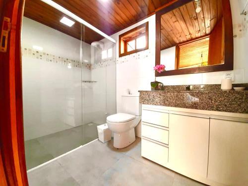 a bathroom with a toilet and a glass shower at Pousada Villa Del Mar in Farol de Santa Marta