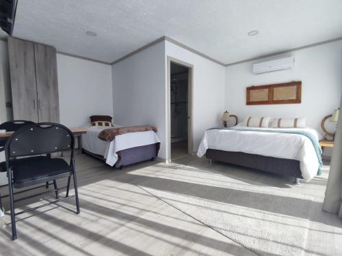 a bedroom with two beds and a chair in it at Casa Hotel Trocha Angosta in Constitución