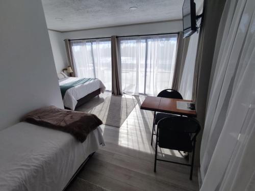 a bedroom with two beds and a desk and a window at Casa Hotel Trocha Angosta in Constitución