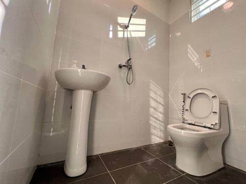 Baño blanco con lavabo y aseo en IJ Lodge, en Miri