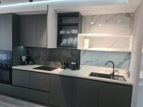 a kitchen with black and white cabinets and a sink at CityView Apartment in Chişinău