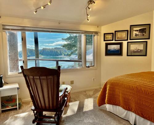 een slaapkamer met een bed, een stoel en een raam bij The Captains View - Cliffside, Ocean Views in Kodiak