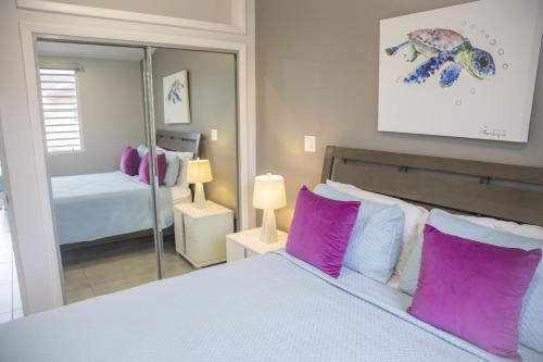 1 dormitorio con cama con almohadas moradas y espejo en 246D South Finger en Jolly Harbour