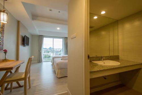 ein Bad mit einem Waschbecken und ein Zimmer mit einem Bett in der Unterkunft Prachuap Grand Hotel in Prachuap Khiri Khan