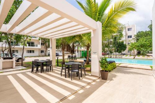 a white pergola with tables and chairs next to a pool at Casa Balam-Exclusivo y Amplio-Ideal Home Office in Playa del Carmen