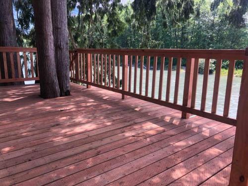 a wooden deck with a tree and a fence at Riverfront Getaway on the Wild and Scenic in Sedro-Woolley