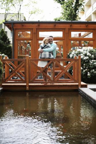 a bride and groom standing on a bridge over the water at Centrum Zdrowia i Wypoczynku Ikar in Kołobrzeg