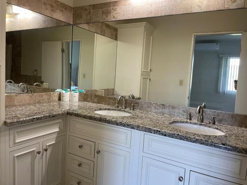 a bathroom with two sinks and a large mirror at Spacious 4bd25ba Retreat Near Hospital & Tumon in Tamuning