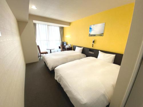 duas camas num quarto de hotel com paredes amarelas em Hotel Continental Fuchu em Fuchu