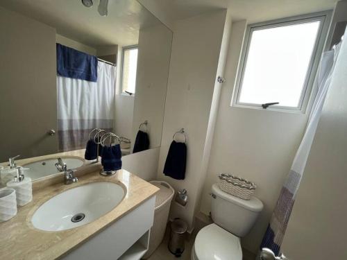 La salle de bains est pourvue d'un lavabo, de toilettes et d'une fenêtre. dans l'établissement Hermoso departamento en Algarrobo, à San Antonio