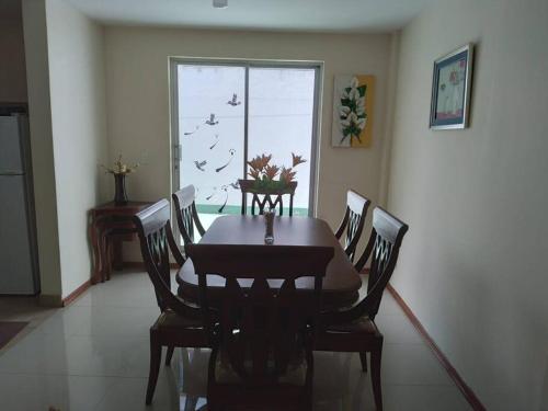 a dining room with a table and chairs and a window at Casa, Hospedaje Turístico. in Otavalo