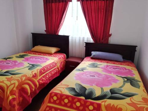 two beds in a room with red curtains at Casa, Hospedaje Turístico. in Otavalo