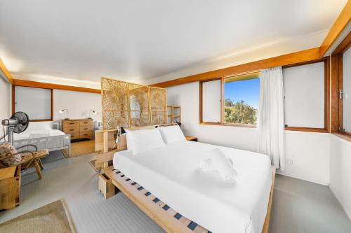 a bedroom with a large white bed and windows at Moongalba in Point Lookout
