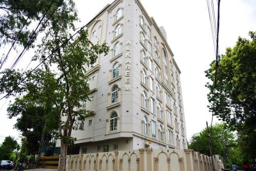 a white building with a fence in front of it at Chic Noir 1 Bedroom Apartment Gulberg in Lahore
