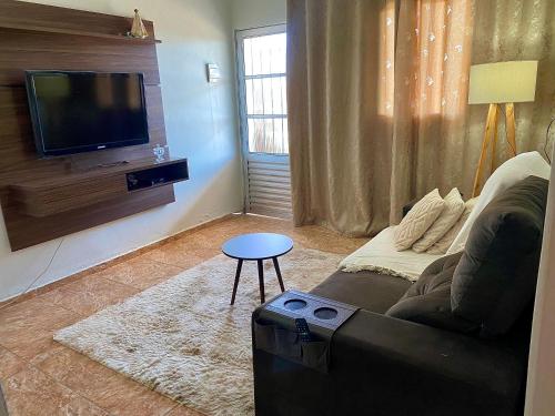 a living room with a couch and a tv at Casa com vista para o por do sol in São Thomé das Letras