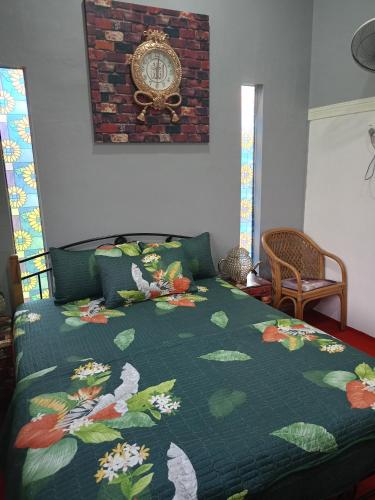 a bedroom with a bed with a green comforter at Homestay ALHAQIM in Pontian Kecil